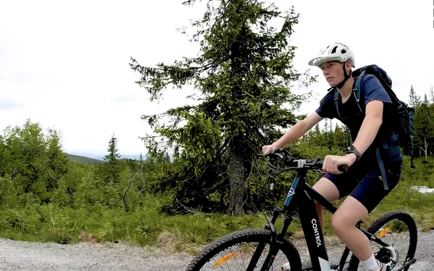 Syklist på Control-elsykkel på grusvei i fjellskogen
